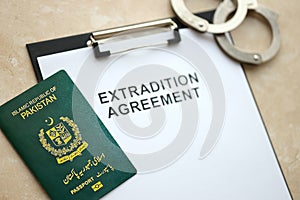 Passport of Pakistan and Extradition Agreement with handcuffs on table