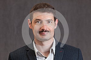 Passport photo of a smiling forties man with a short mustache