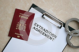 Passport of Spain and Extradition Agreement with handcuffs on table