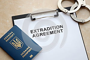 Passport of Ukraine and Extradition Agreement with handcuffs on table