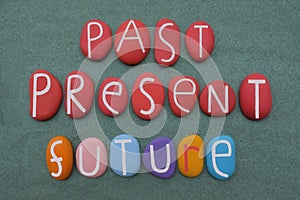 Past, Present, Future, motivational slogan composed with multicolored stone letters over green sand