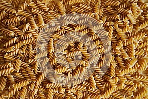 Pasta background - helix on a wooden surface. Edible texture