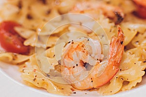 Pasta bavette with fried shrimps, bechamel sauce, mint leaf, garlic, tomatoes, chili on white plate, top view, italian