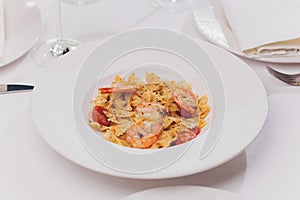 Pasta bavette with fried shrimps, bechamel sauce, mint leaf, garlic, tomatoes, chili on white plate, top view, italian