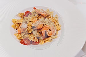 Pasta bavette with fried shrimps, bechamel sauce, mint leaf, garlic, tomatoes, chili on white plate, top view, italian