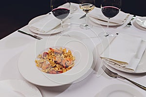 Pasta bavette with fried shrimps, bechamel sauce, mint leaf, garlic, tomatoes, chili on white plate, top view, italian