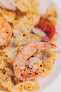 Pasta bavette with fried shrimps, bechamel sauce, mint leaf, garlic, tomatoes, chili on white plate, top view, italian