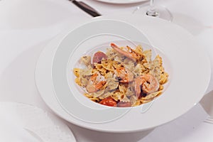 Pasta bavette with fried shrimps, bechamel sauce, mint leaf, garlic, tomatoes, chili on white plate, top view, italian