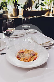 Pasta bavette with fried shrimps, bechamel sauce, mint leaf, garlic, tomatoes, chili on white plate, top view, italian