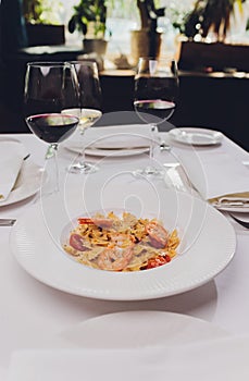 Pasta bavette with fried shrimps, bechamel sauce, mint leaf, garlic, tomatoes, chili on white plate, top view, italian