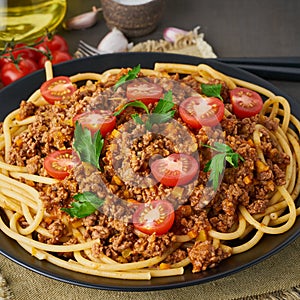 Pasta Bolognese bucatini with mincemeat and tomatoes, dark wooden background, closeup