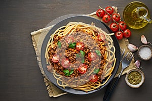 Pasta Bolognese bucatini with mincemeat and tomatoes, dark wooden background, top view, copy space