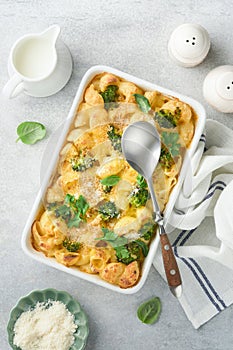 Pasta Broccoli casserole. Baked Mac and cheese with broccoli, cream sauce and parmesan on gray light concrete table background.