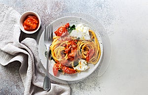 Pasta bucatini with tomato sauce, tomatoes, spinach soft cheese and parmesan cheese
