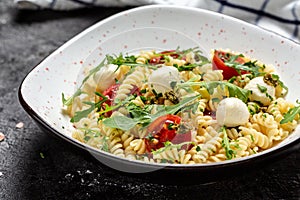 Pasta Caprese salad with cherry tomatoes and mozzarella cheese. Food recipe background. Close up