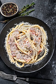 Pasta Carbonara on black plate with parmesan, bucatini. Black background. Top view