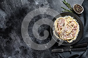 Pasta Carbonara on black plate with parmesan, bucatini. Black background. Top view. Copy space