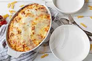 Pasta casserole with fusilli noodles, bolognese and bechamel sauce. Topped with mozzarella cheese crust on white background