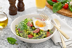 Pasta cavatappi with spinach pesto, tomatoes and fried egg in bowl served for lunch