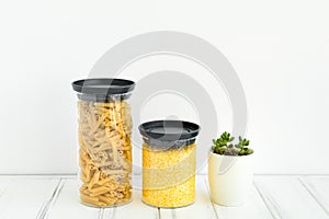 Pasta and cereals in glass jars on white background. Organized kitchen and healthy eating concept
