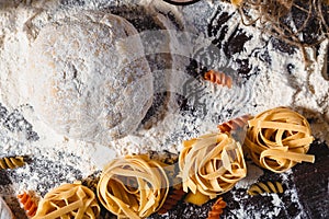 Pasta on dark wooden background with dough, eggs, oil and flour close-up macro