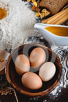 Pasta on dark wooden background with eggs, oil and flour close-up macro