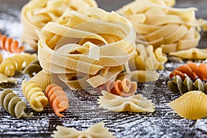 Pasta on dark wooden background with flour close-up macro