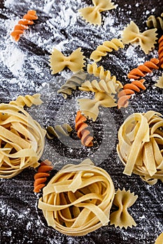 Pasta on dark wooden background with flour close-up macro