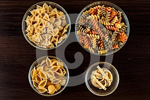 Pasta on dark wooden background in glass dishes close-up macro