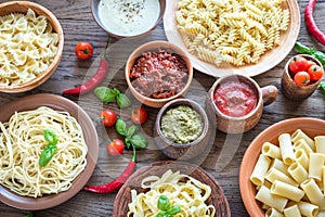 Pasta with different kinds of sauce on the wooden background