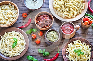 Pasta with different kinds of sauce on the wooden background