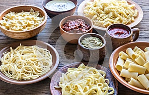 Pasta with different kinds of sauce on the wooden background