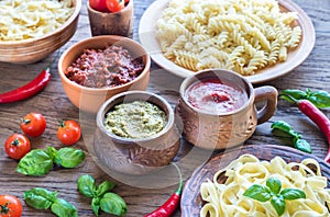 Pasta with different kinds of sauce on the wooden background