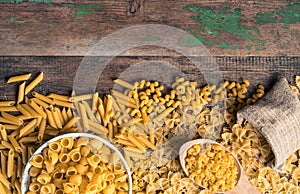 Pasta of different types on a wooden table. Top view with space to copy