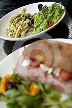 Pasta Dish with Green Pesto and Salad on a White Plate