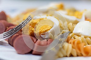 Pasta with eggs and sausages on plate
