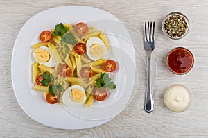 Pasta with eggs, tomatoes, parsley, fork, bowls with condiment,