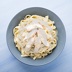 Pasta fettuccine alfredo with chicken and parmesan on blue wooden background top view