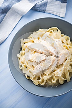 Pasta fettuccine alfredo with chicken and parmesan on blue wooden background top view