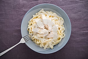 Pasta fettuccine alfredo with chicken and parmesan on dark canvas background top view