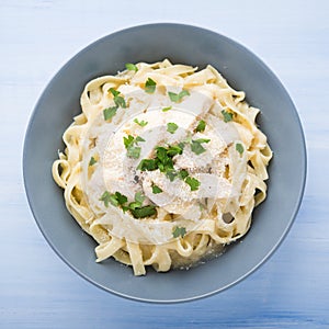 Pasta fettuccine alfredo with chicken, parmesan and parsley on blue wood background top view