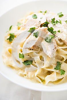 Pasta fettuccine alfredo with chicken, parmesan and parsley on white background close up