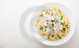 Pasta fettuccine alfredo with chicken, parmesan and parsley on white background top view