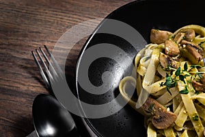 Pasta fettucine with mushrooms and creamy pesto sauce on rustic wooden background