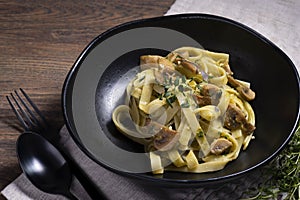 Pasta fettucine with mushrooms and creamy pesto sauce on rustic wooden background