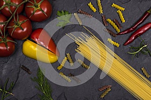 Pasta, fresh, sliced vegetables, lying on a black background . Top view