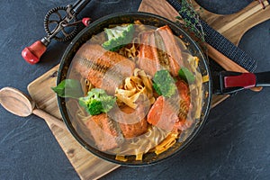 Pasta with fried fish on rustic table background