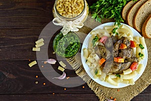 Pasta and fried goose liver (chicken, duck) with pesto and tomato on a wooden background.