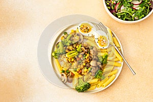 Pasta with fried mushrooms and broccoli, green peas and corn, fresh mix salad