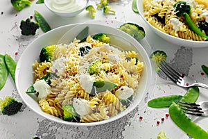 Pasta with green vegetables broccoli, Mange tout and creamy sauce in white plate